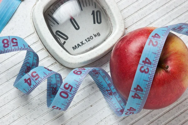 Apple and measuring tape on the floor scales
