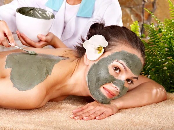 Young woman having clay body mask.