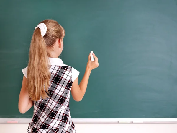 Schoolchild writing on blackboard.