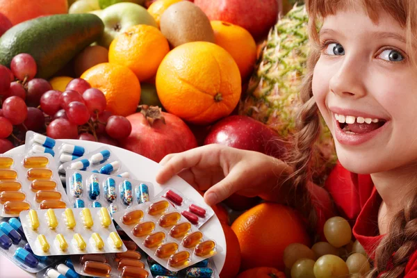 Child with fruit and vitamin pill.