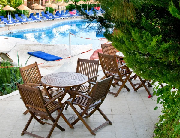 Hotel patio with tables and chairs next to swimming pool.