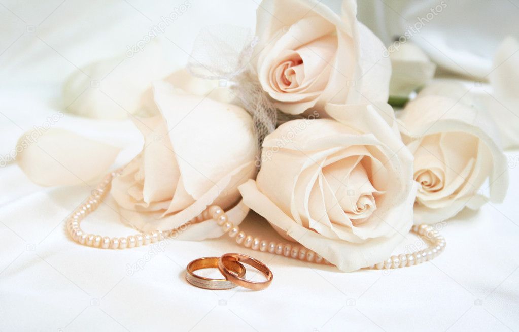 Wedding rings and roses as background