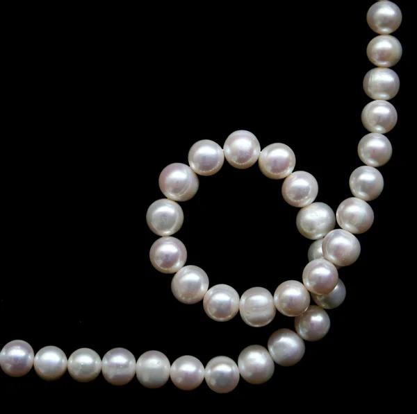 White pearls on the black silk as background