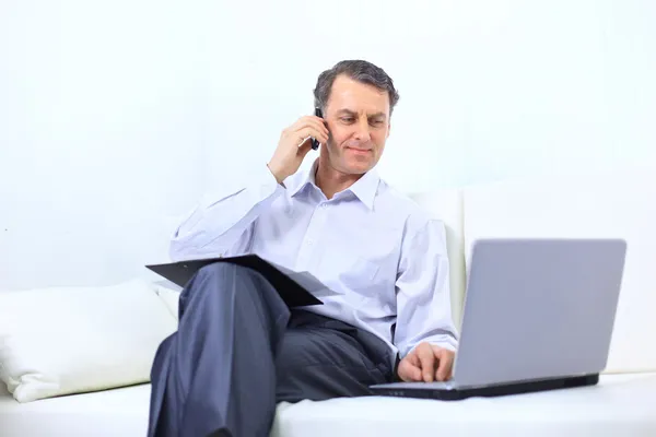 Entrepreneur working from home looking very relaxed in his sofa browsing th