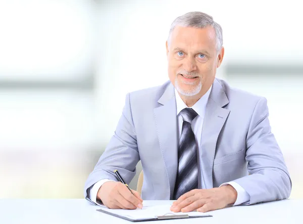 Portrait of smiling Senior business man writing on notepad