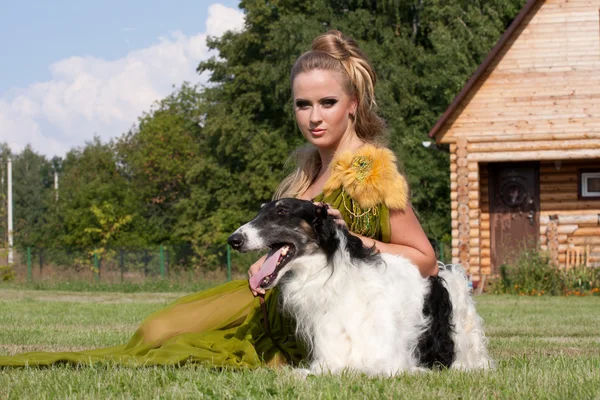 The woman in a beautiful old style dress with borzoi dogs