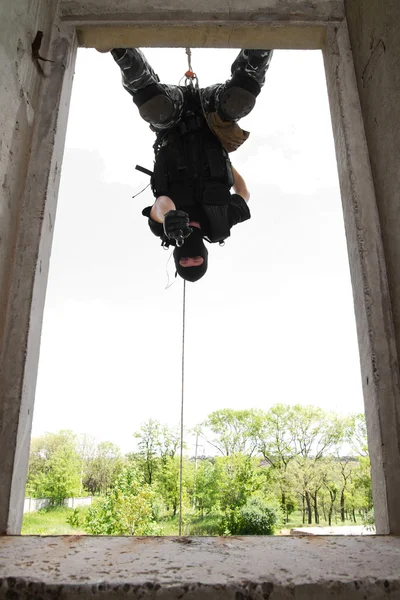 Soldier in black mask hanging on rope with pistol