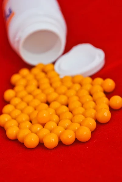 Vitamin pills and a plastic container isolated on red