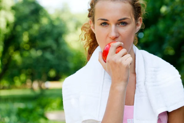 Young woman after sport workout eating apple