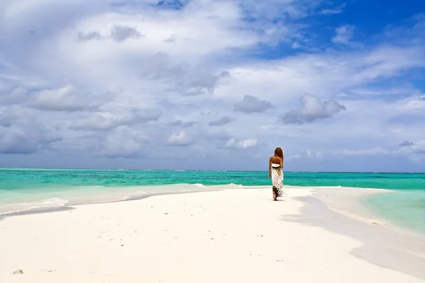 Beautiful view of slender young woman walking alone on ocean beach