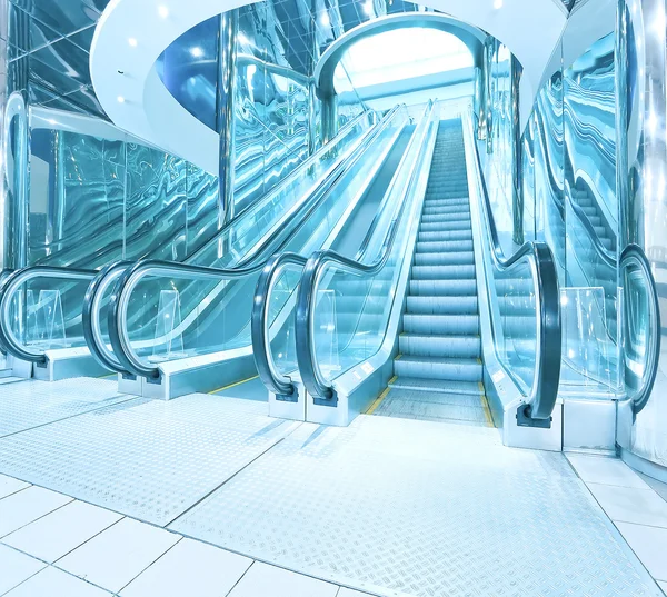 Contemporary moving escalator stairs inside business blue hall