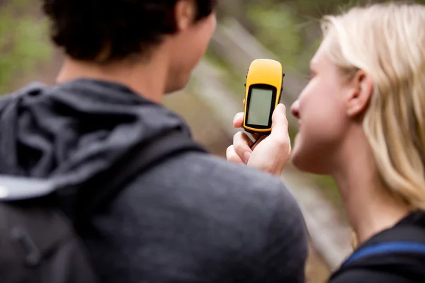 A couple outdoors in the forest using a GPS