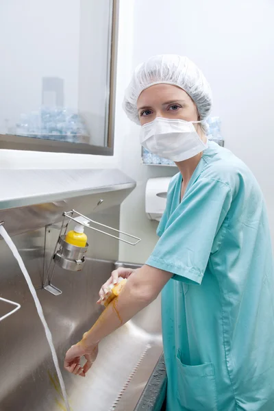 Medical woman in mask washing hands