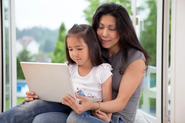 Cute daughter and mother with laptop