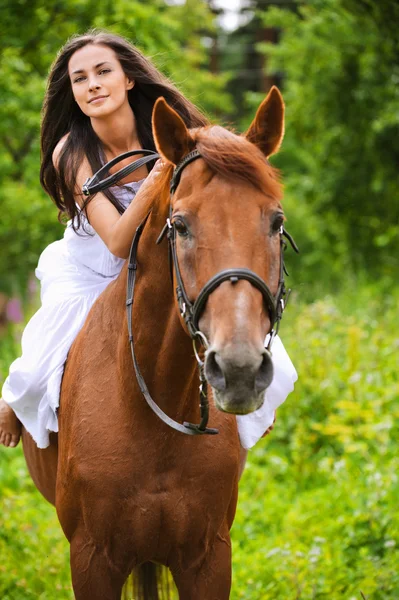 Young brunette woman rides a horse