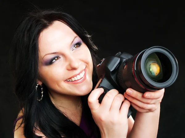 Photographer woman holding camera over dark background