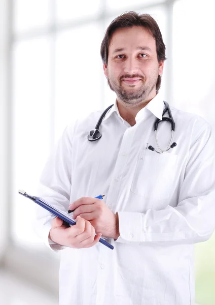 Smiling medical doctor with stethoscope writing a receipt in modern new hos