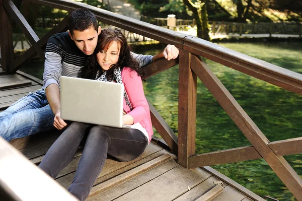 Young couple, male and female sitting in park and studing and workind toget