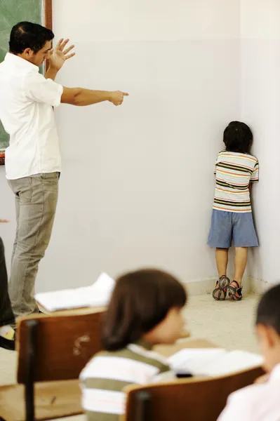 Punishing children in classroom, angry teacher and kid in corner