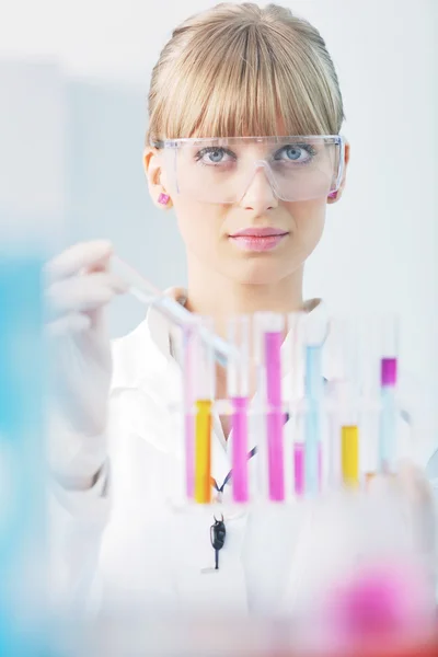 Female researcher holding up a test tube in lab