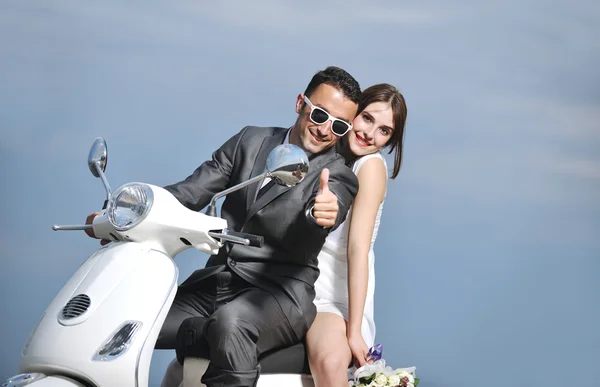 Just married couple on the beach ride white scooter