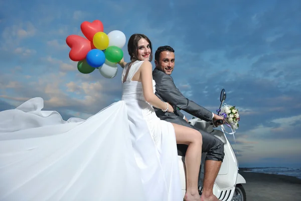 Just married couple on the beach ride white scooter