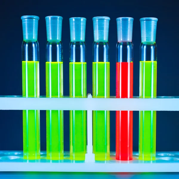 Six test tubes, one red