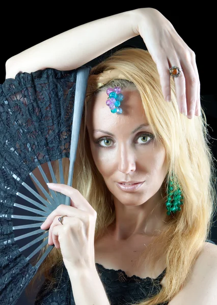 The beautiful young woman with long blonde hair and fan and jewellry on