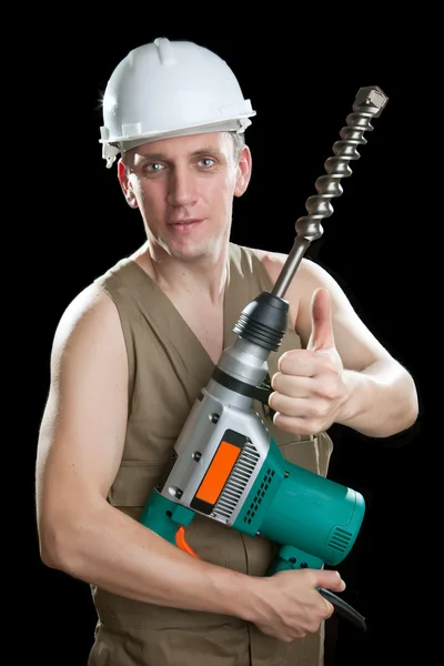 The builder in a protective helmet holds the professional puncher-hammer wi