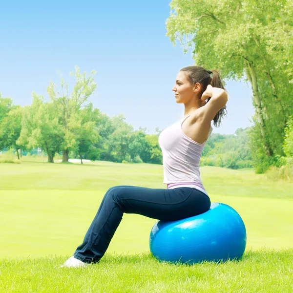 Fitness women exercising with pilates ball outdoors