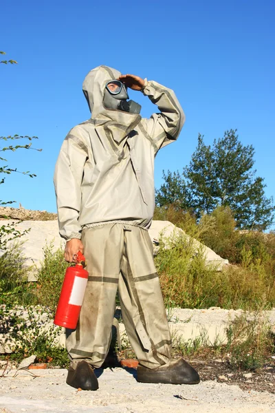Man in protective suit and a fire extinguisher looks into the distance