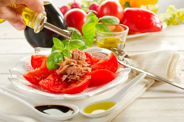 Olive oil over salad with tuna and tomatoes