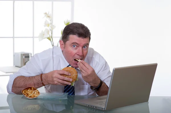 Manager eating unhealthy food at work place