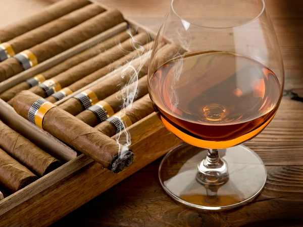 Cuban cigar and cognac on wood background