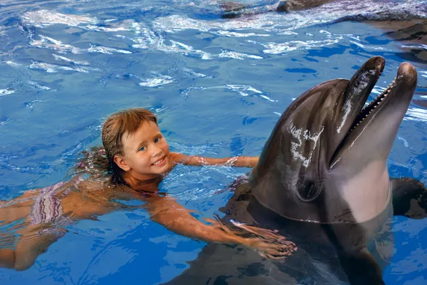 Child and dolphin in blue water.