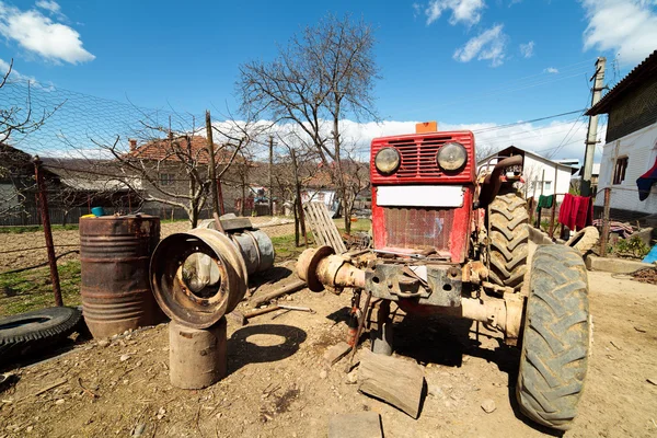 Beaten up old tractor in the countryside, on a jack