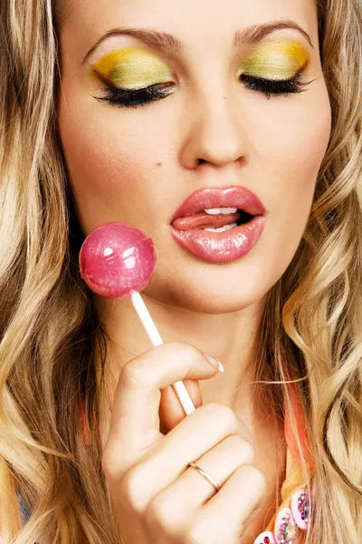 Beutiful woman with creative makeup holding a candy