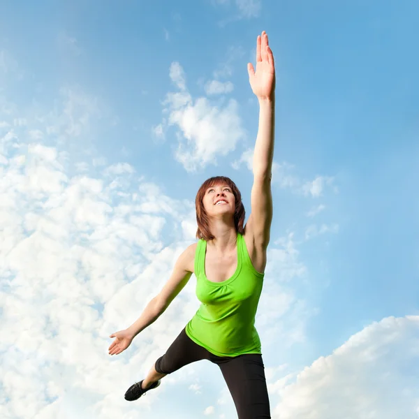 Athletic woman balancing in front of blue sky