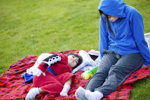 Teenager caring for disabled child at park