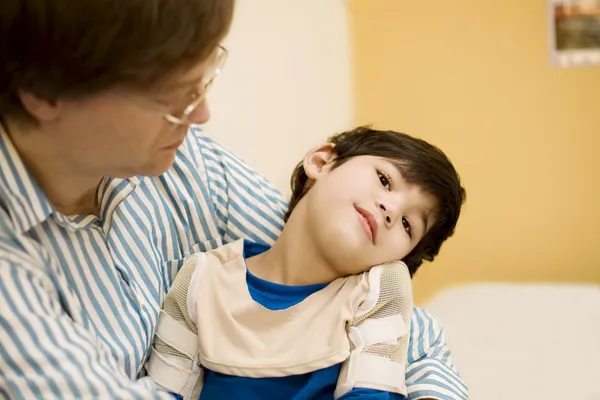 Father holding disabled son in doctor\'s office