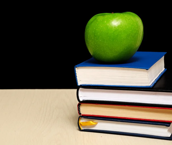 School books with apple on desk