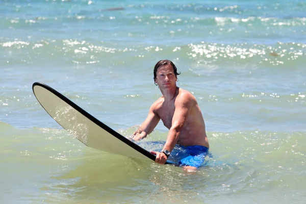 Fit middle aged man surfing on beach in summer