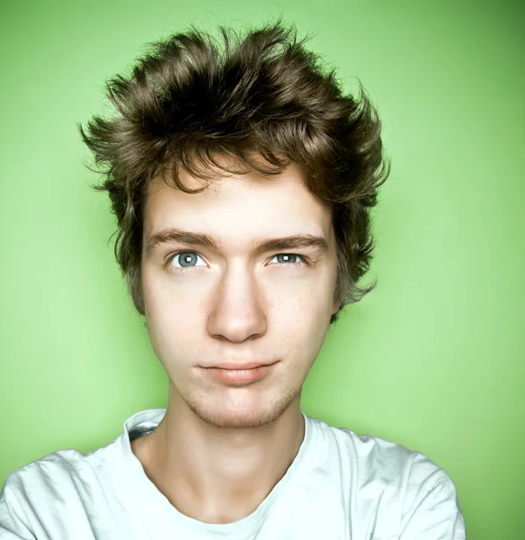 Portrait of a teenager looking up, on a green background.