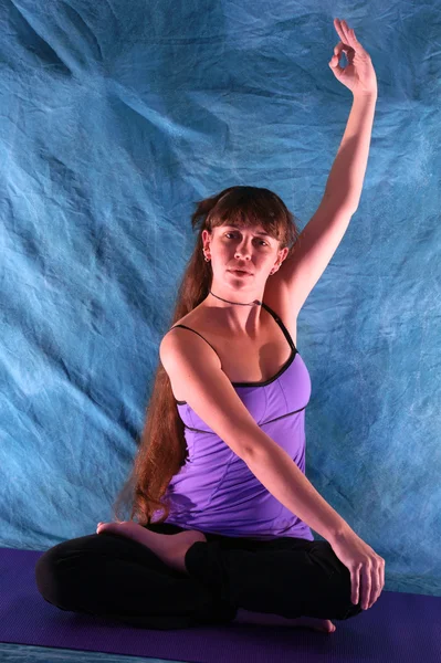 Woman in half lotus yoga prayer position with arm up hand in om
