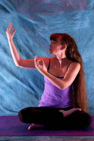 Woman in half lotus yoga with hands in dancing shiva position