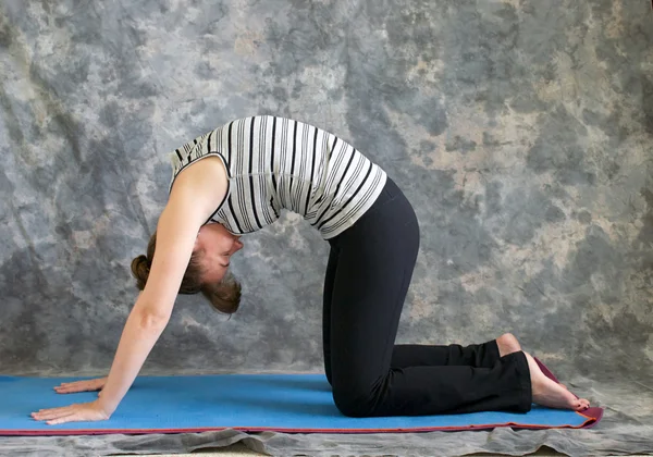 Woman doing Yoga posture Marjaryasana or cat pose