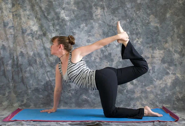 Woman doing Yoga posture Vyaghrasana The Tiger Pose variation