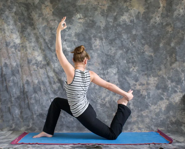 Woman doing Yoga posture King Arthurs pose variation