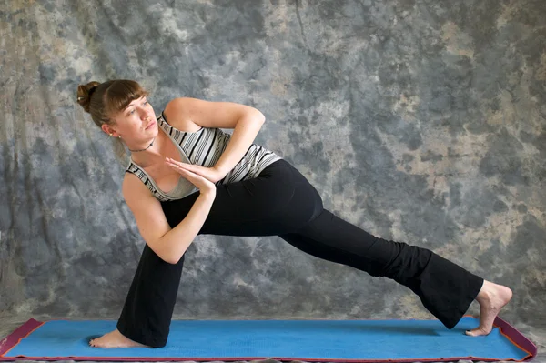 Woman doing Yoga posture Parivrtta Parsvakonasana or Revolved Ex