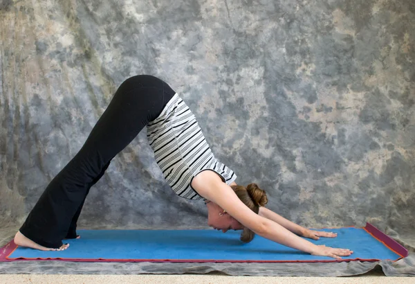 Young woman doing Yoga posture Adho Mukha Svanasana or Downward